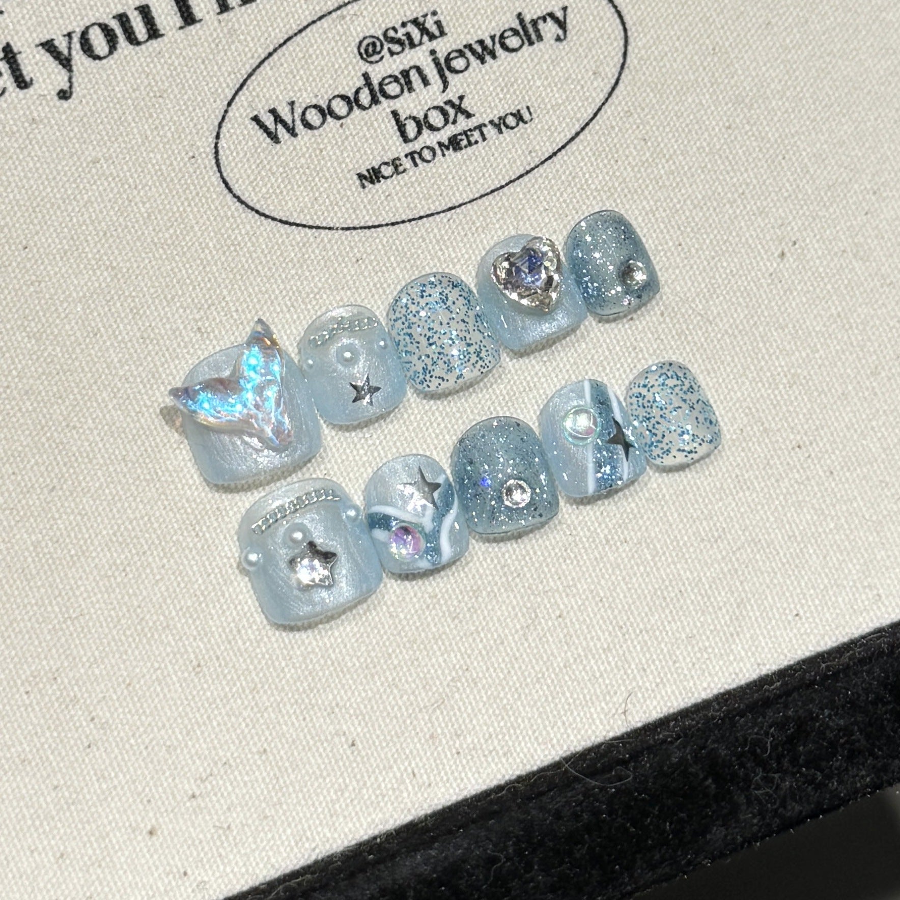 Set of blue glittery earrings on a branded wooden jewelry box